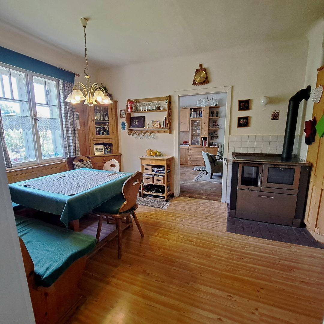Gemütlicher Essbereich mit Holzboden, traditionellem Ofen und rustikalen Holzmöbeln.
