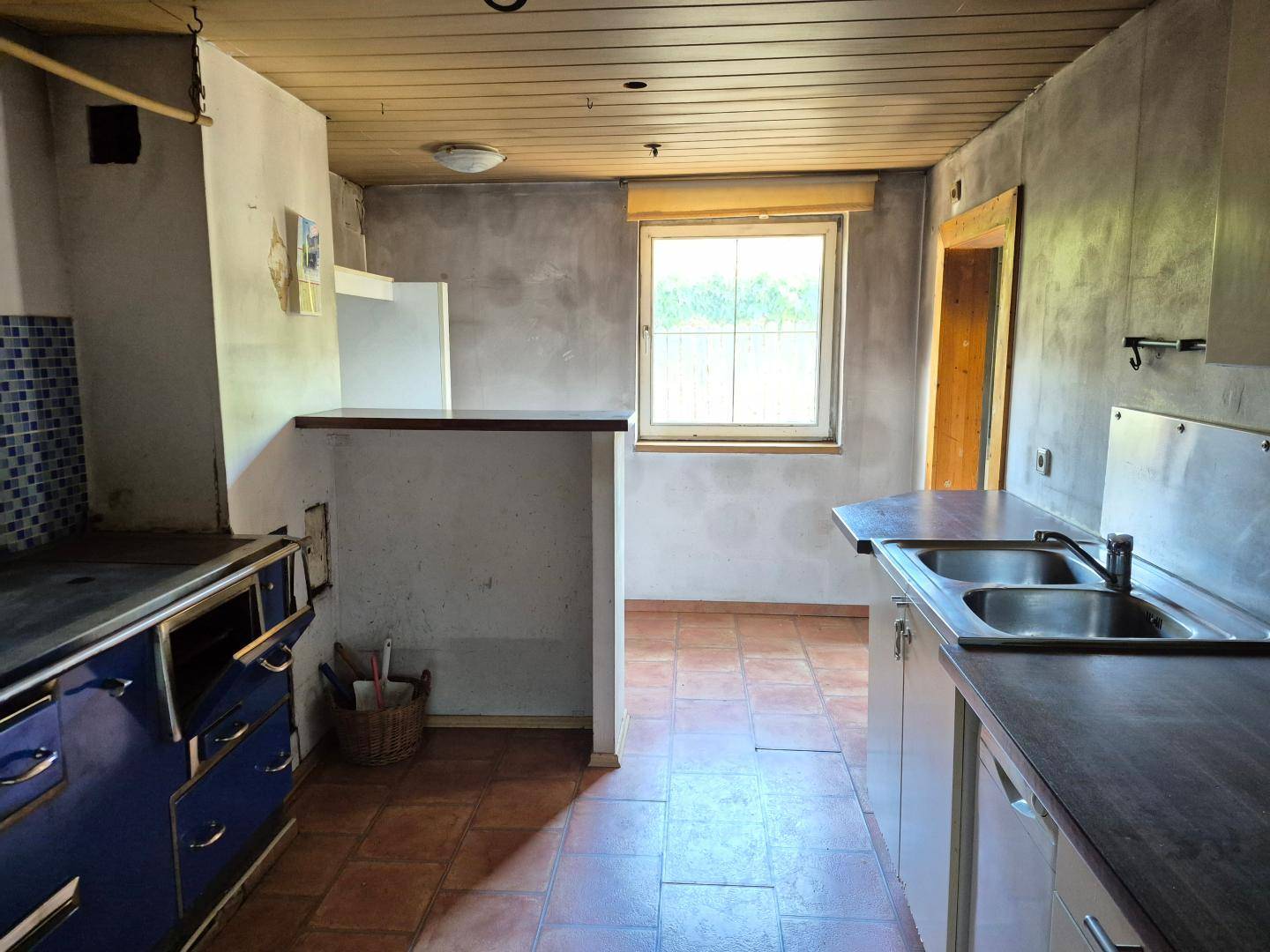 Einfache Küche mit Terrakottafliesen und Holzdecke, bereit für eine Modernisierung.
