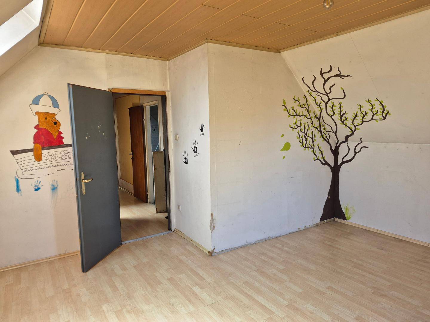 Kinderzimmer im Dachgeschoss mit Schrägen, Holzboden und Wandmalerei.