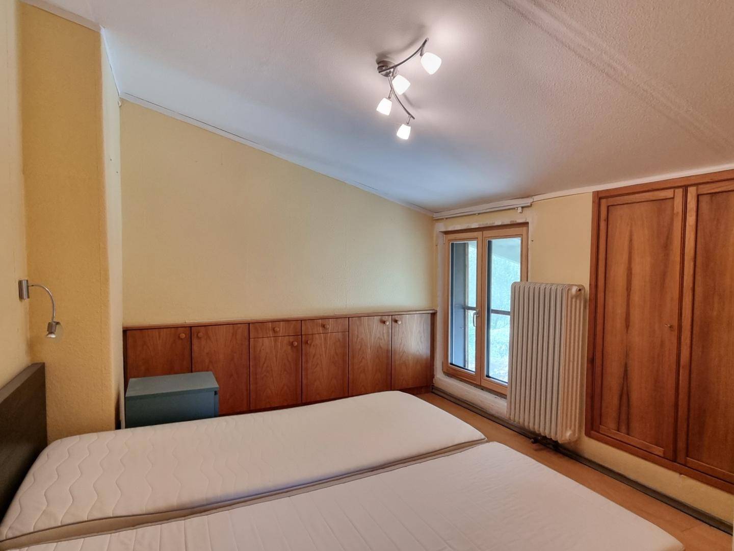 Schlafzimmer mit zwei Einzelbetten, Einbauschränken und Dachschräge.
