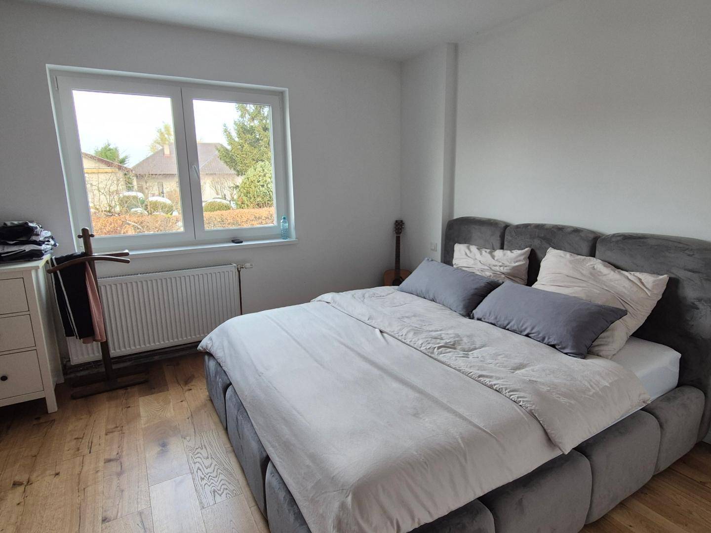 Gemütliches Schlafzimmer mit Holzboden, großem Bett und Blick ins Grüne durch das Fenster.