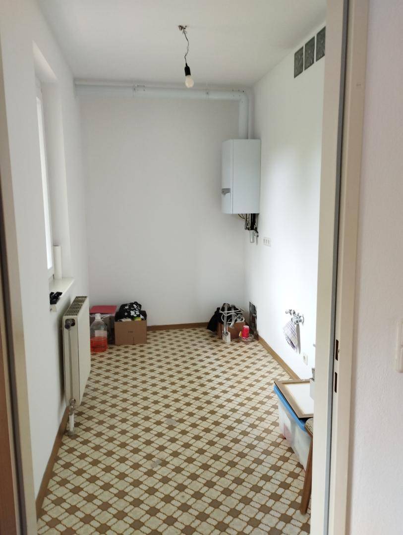 Funktionaler Hauswirtschaftsraum mit Gastherme, Fenster und gemusterten Bodenfliesen.