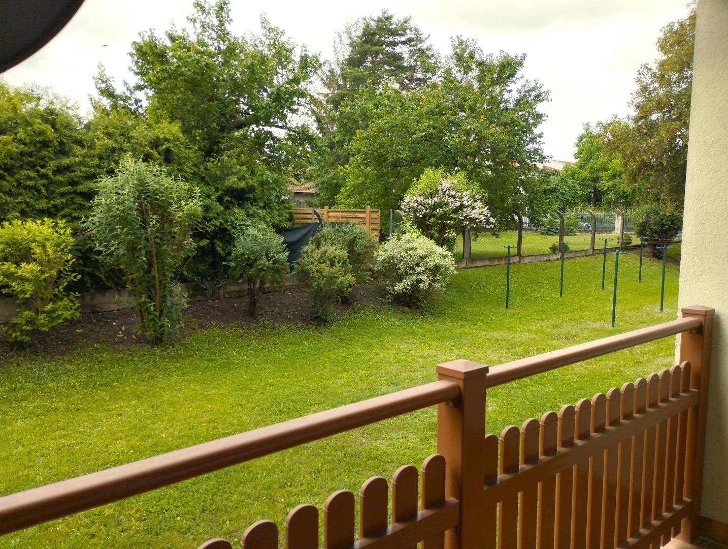 Weitläufiger grüner Garten mit Bäumen und Sträuchern, gesehen von einem Balkon.