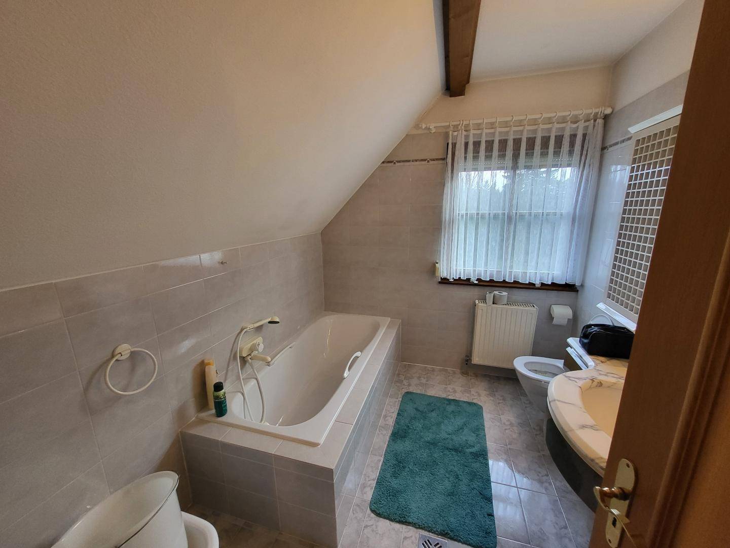 Badezimmer im Dachgeschoss mit Badewanne, WC, Waschbecken und Fenster.