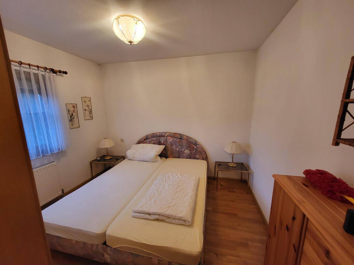 Schlafzimmer mit zwei Einzelbetten, Holzboden und Fenster.