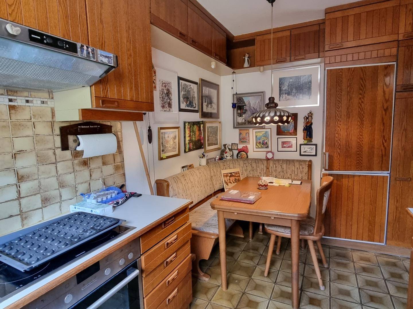 Gemütliche Wohnküche mit Holzeinrichtung, Essecke und vielen Bildern an der Wand.