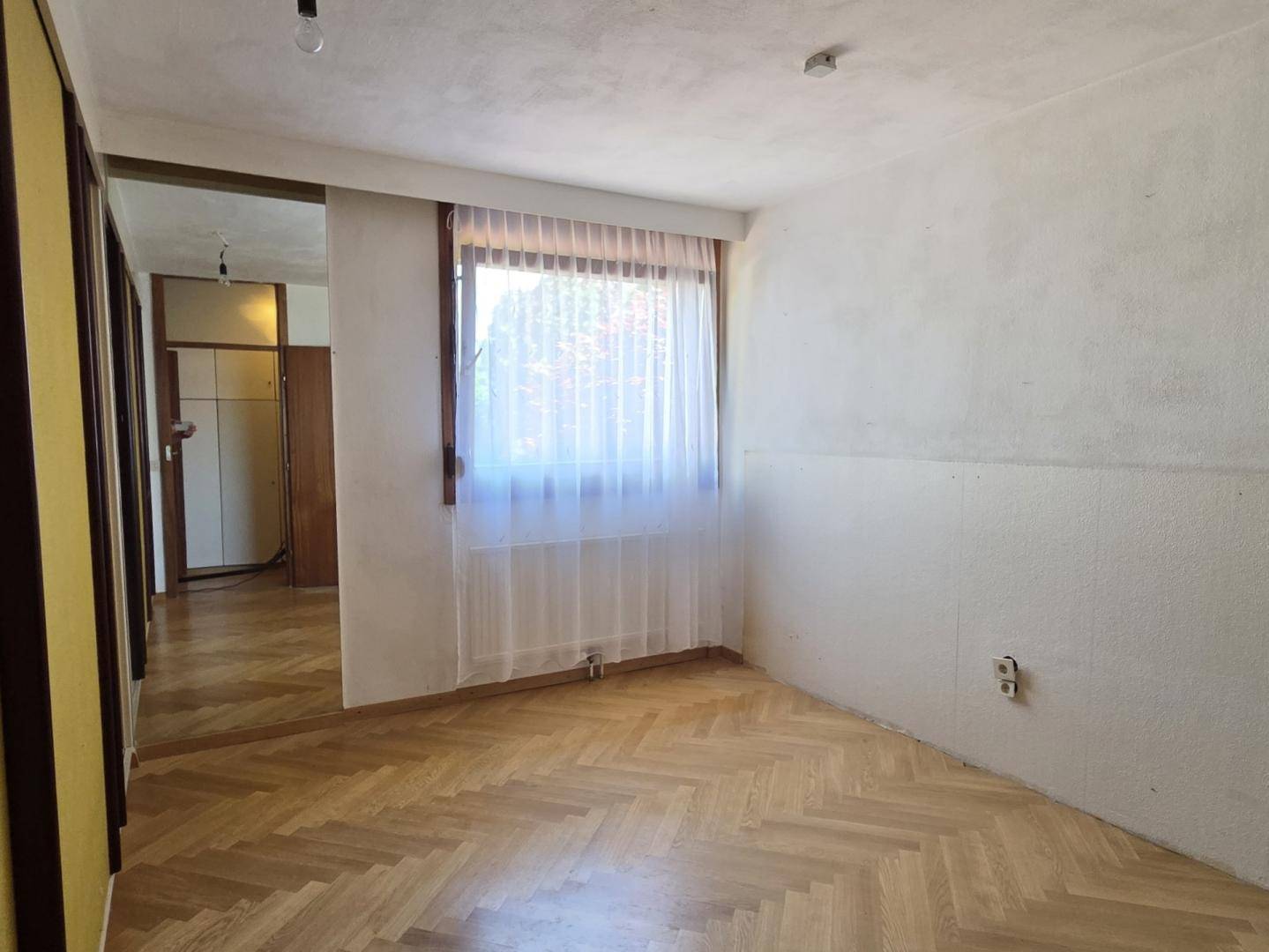 Helles Schlafzimmer mit Parkettboden und Spiegelschränken, bereit zur individuellen Gestaltung.