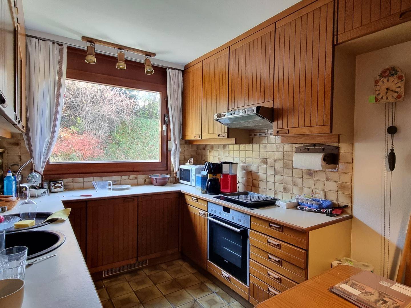 Traditionelle Holzküche mit Einbauschränken, Fenster und Blick ins Grüne.