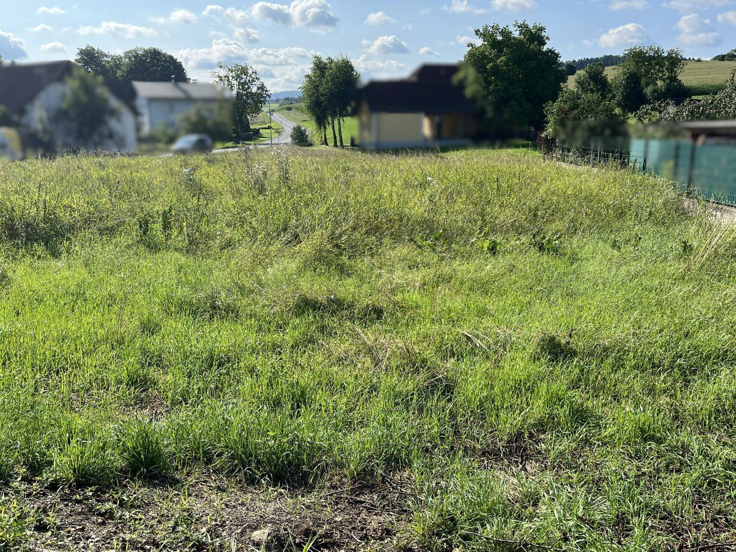 Blick über ein unbebautes Grundstück mit hohem Gras und ländlicher Umgebung.