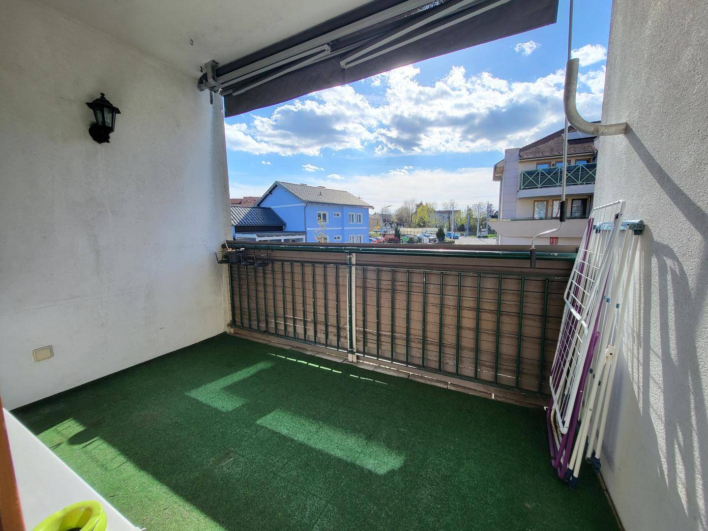 Kleiner Balkon mit Kunstrasen und Blick auf die umliegende Nachbarschaft.