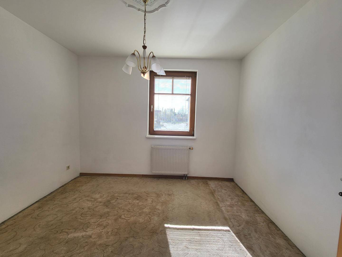 Helles Zimmer mit Teppichboden und einem Fenster mit Blick nach draußen.