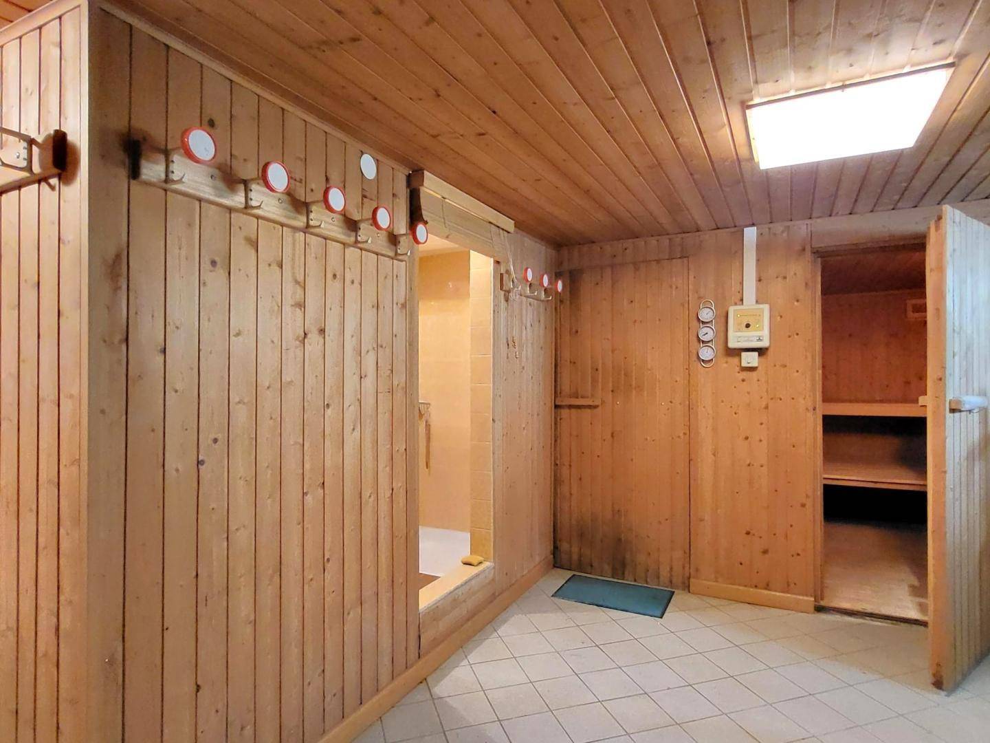 Geräumiger Saunabereich mit holzvertäfelten Wänden und Bänken, bereit zur Entspannung.