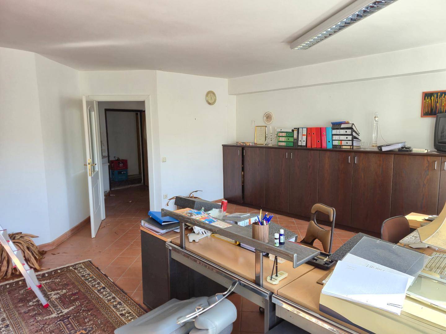 Büroansicht mit offenem Durchgang zu einem weiteren Raum und praktischen Aufbewahrungsschränken.