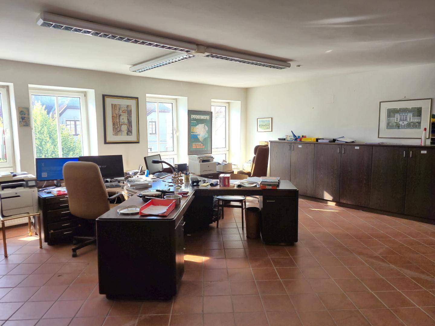 Geräumiges Büro mit umfangreichen Aktenschränken, mehreren Schreibtischen und viel Tageslicht.