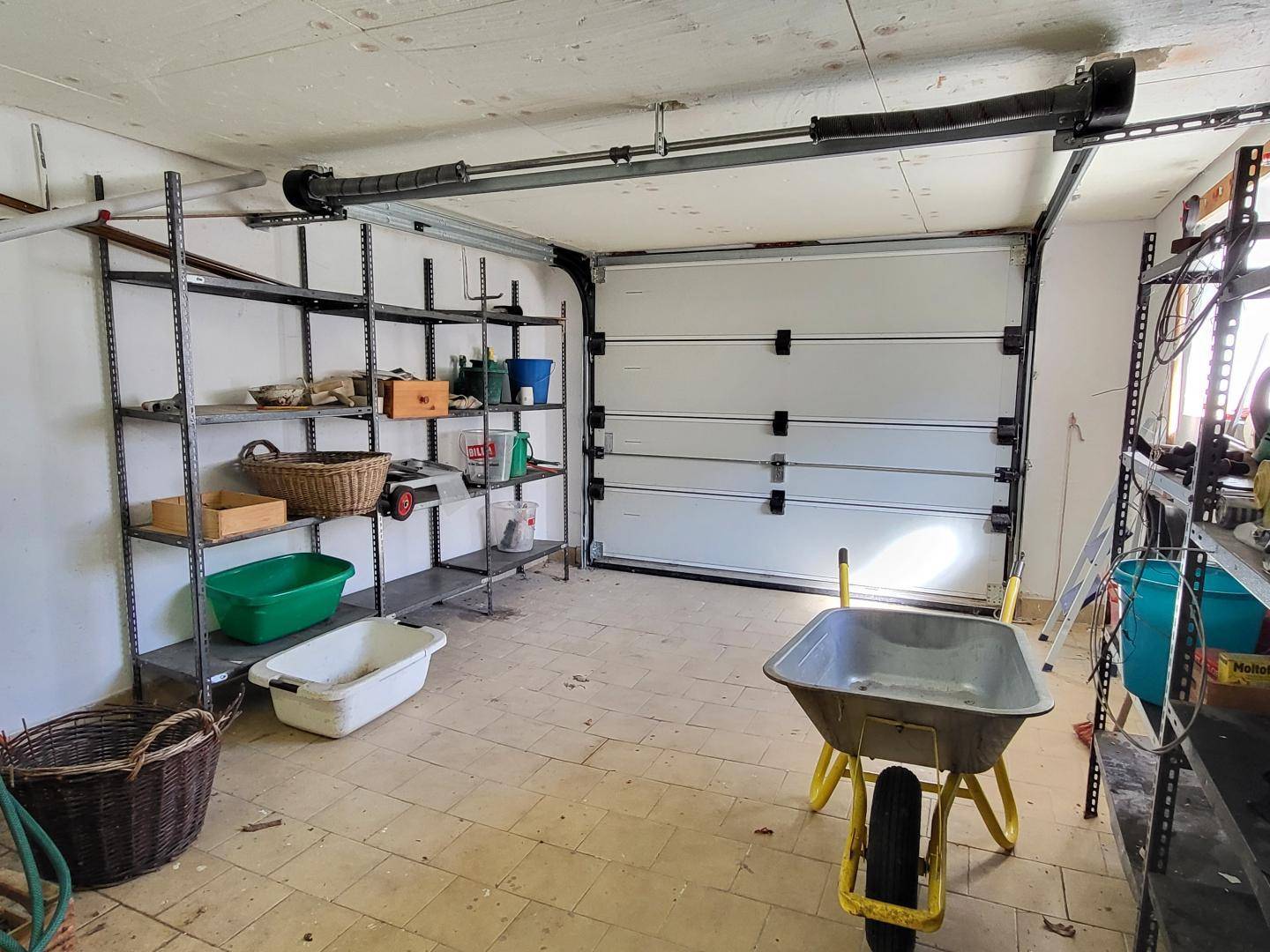 Geräumige Garage mit Regalen für Lagerung und automatischem Garagentor.