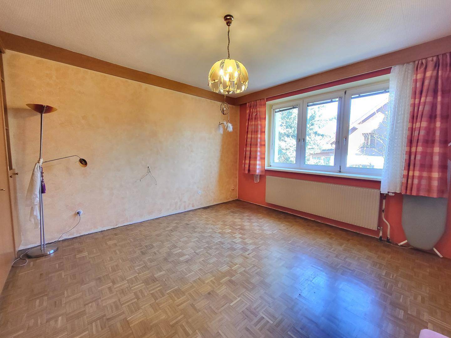 Helles Zimmer mit Parkettboden und Fenstern, bereit zur individuellen Gestaltung.