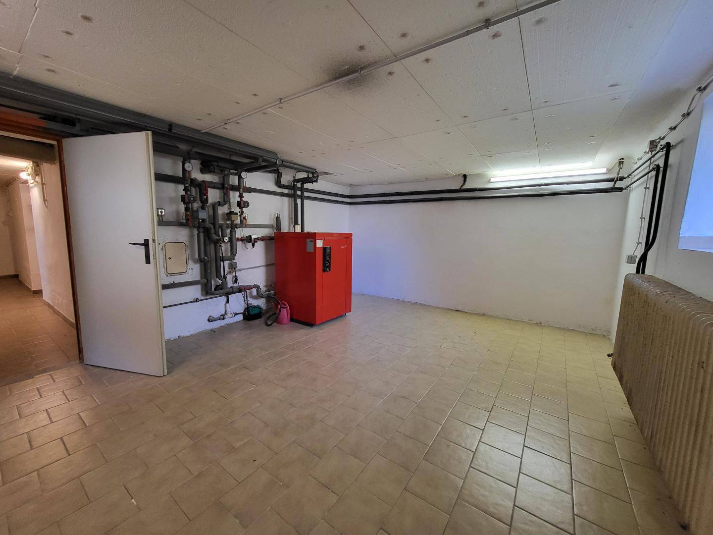 Heizungsraum im Keller mit moderner Heizungsanlage und Fliesenboden.