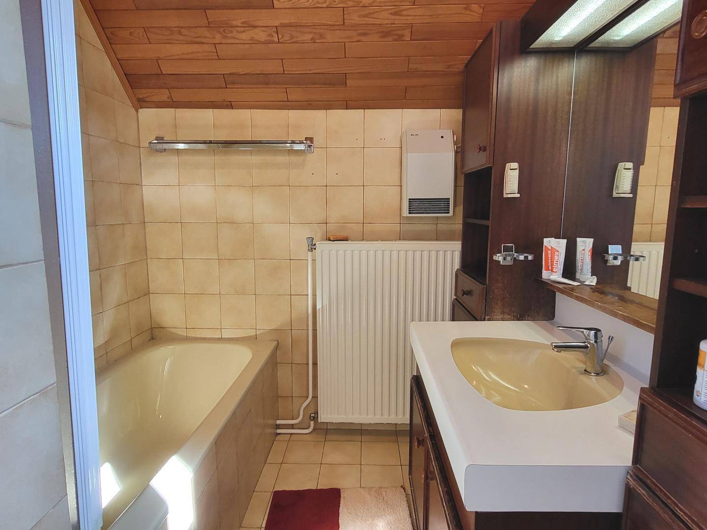 Badezimmer mit Badewanne, Waschbecken und Holzschrank im traditionellen Stil.