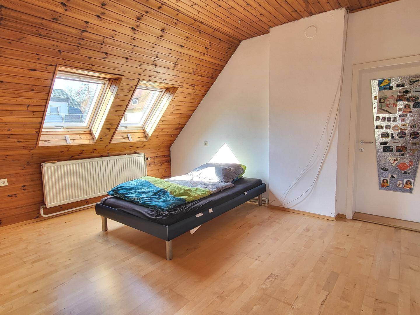Gemütliches Schlafzimmer im Dachgeschoss mit Holzverkleidung und Dachfenstern.