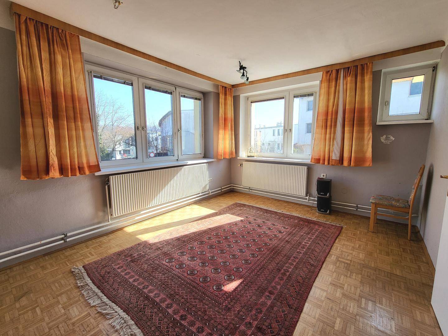 Geräumiges Zimmer mit Parkettboden, großen Fenstern und viel Tageslicht.