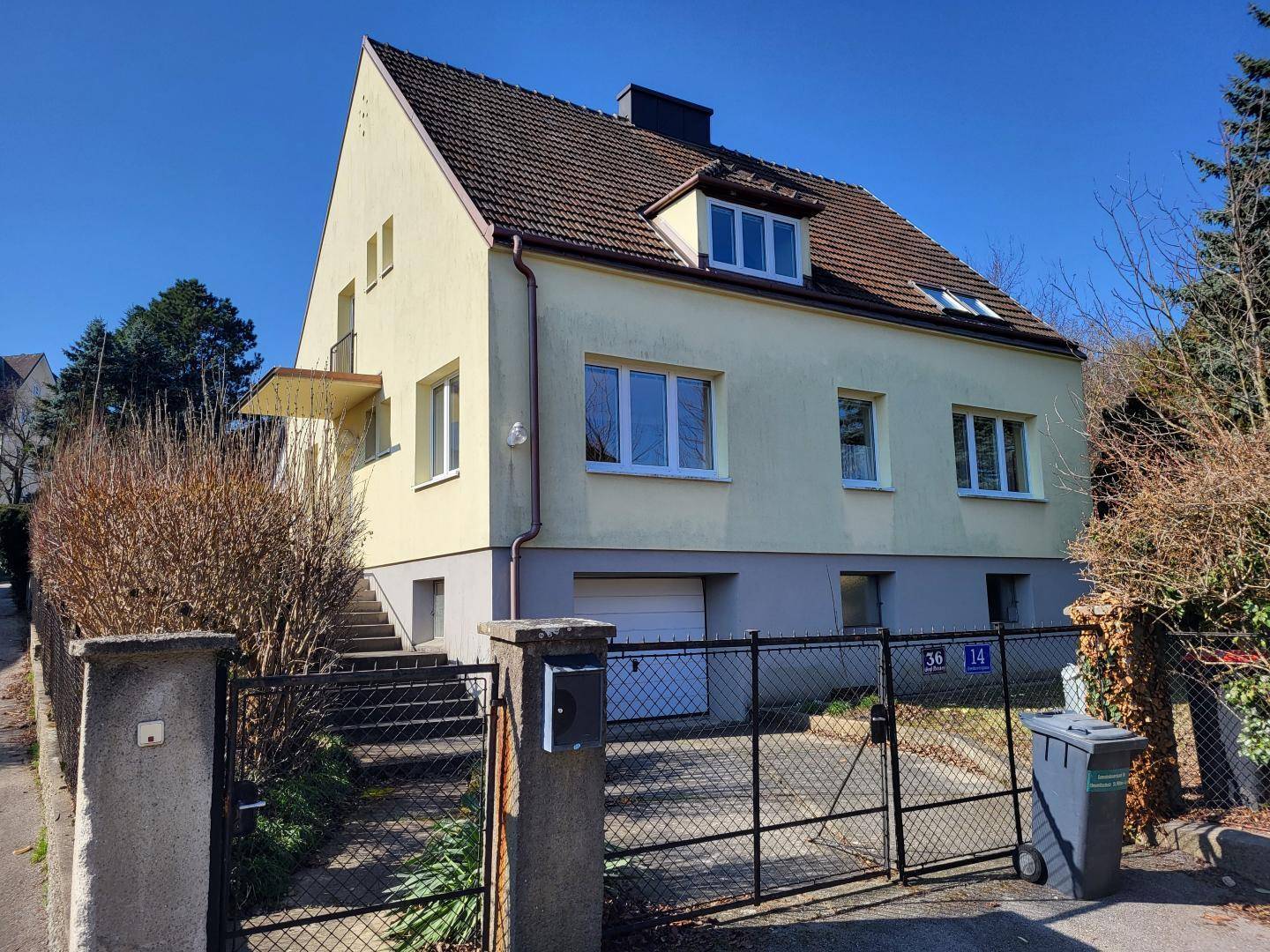 Einfamilienhaus mit Garagenzufahrt und Eingangsbereich von der Straße aus.