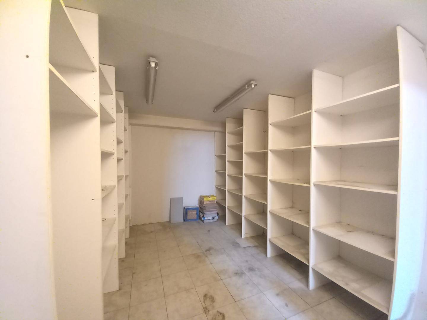 Praktischer Abstellraum mit vielen weißen Regalen und Fliesenboden für zusätzlichen Stauraum.
