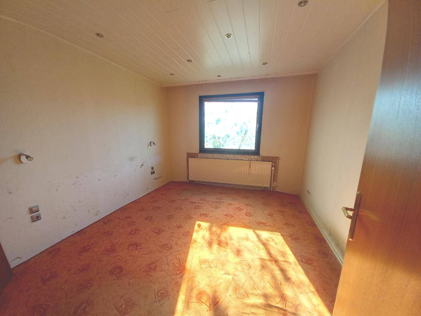 Schlafzimmer mit Teppichboden, Fenster und Heizkörper, bereit zur individuellen Gestaltung.