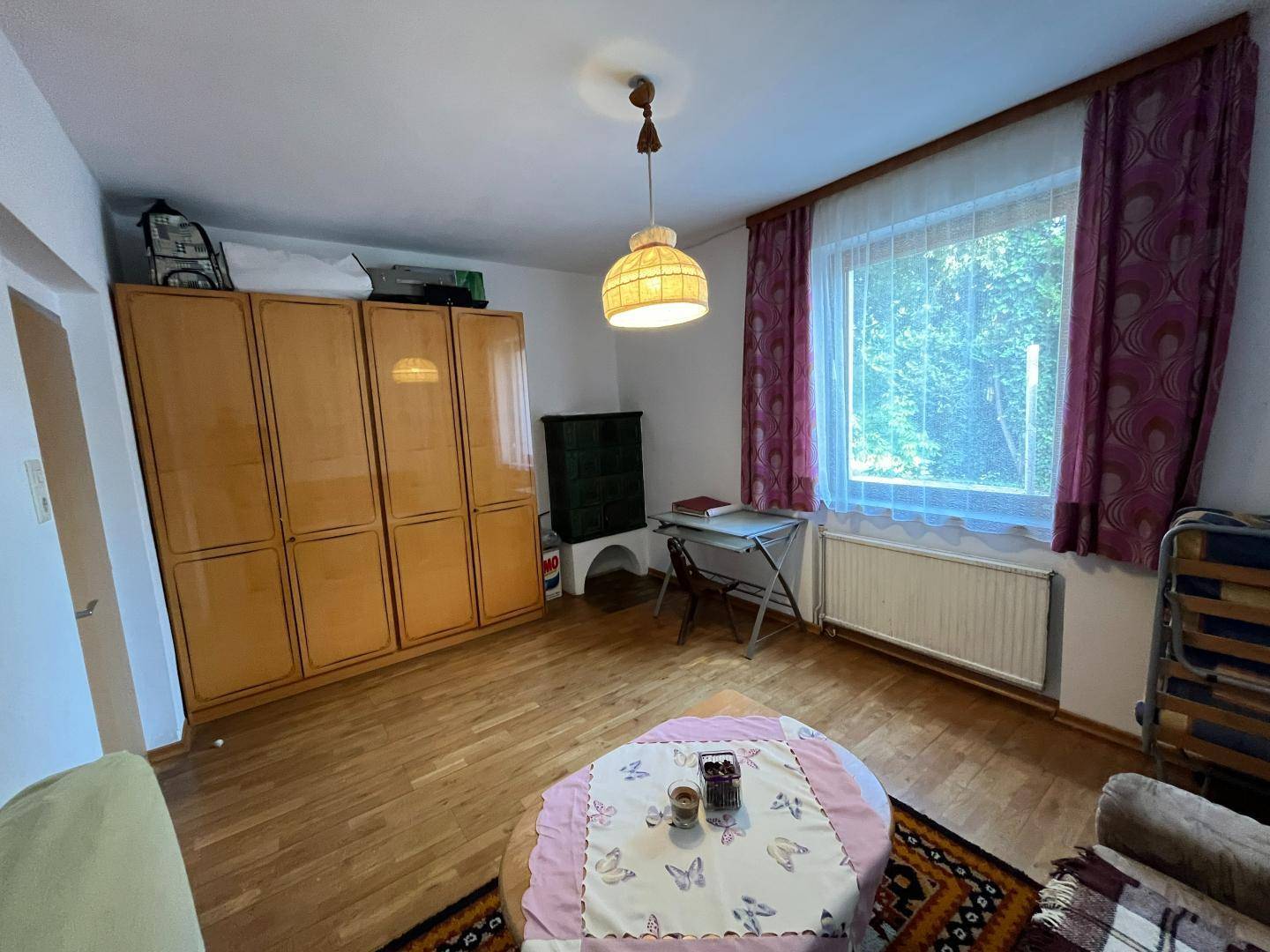 Geräumiges Schlafzimmer mit großem Kleiderschrank, Holzfußboden und Fenster.