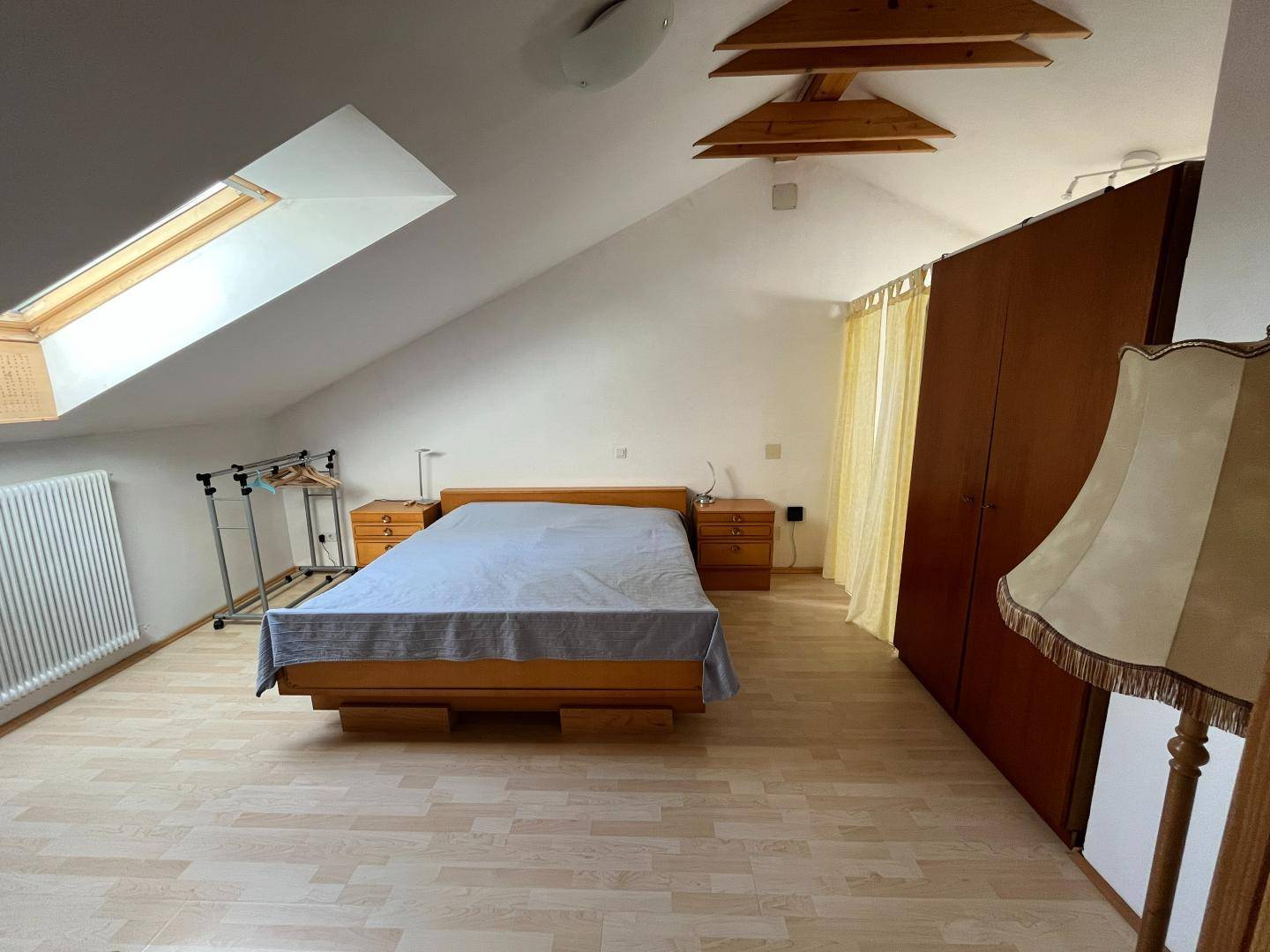 Schlafzimmer im Dachgeschoss mit Dachfenster, Holzfußboden und Kleiderschrank.