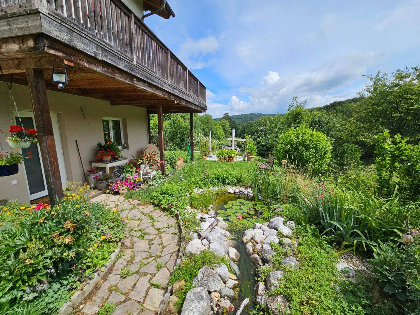 Naturnaher Gartenbereich mit Teich, Steinen und üppiger Bepflanzung.