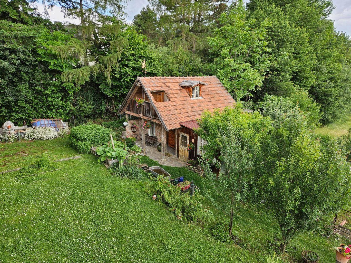 Kleines Gartenhaus umgeben von einem weitläufigen, grünen Gartenbereich.