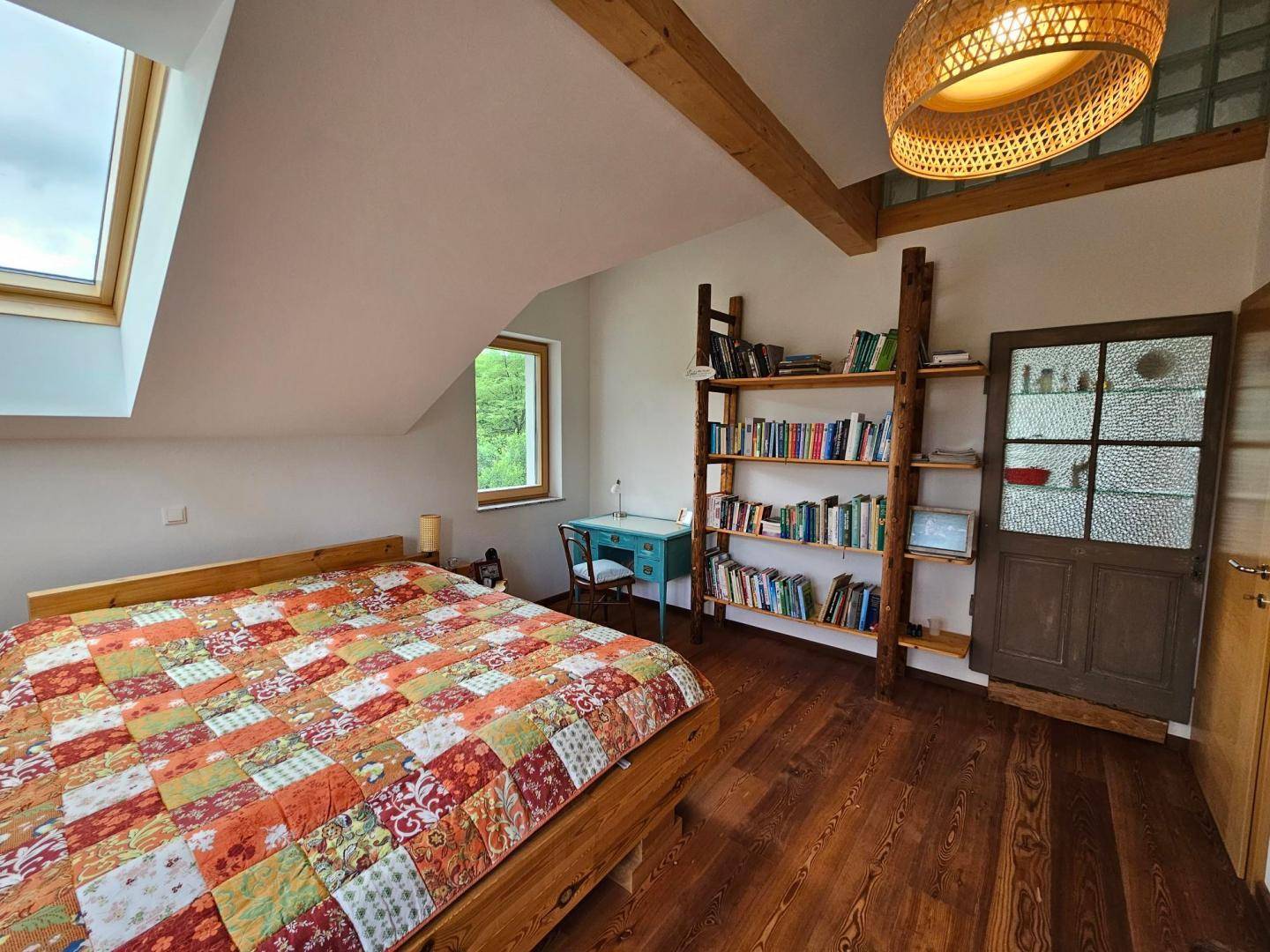 Gemütliches Schlafzimmer im Dachgeschoss mit Holzboden und Dachfenster.
