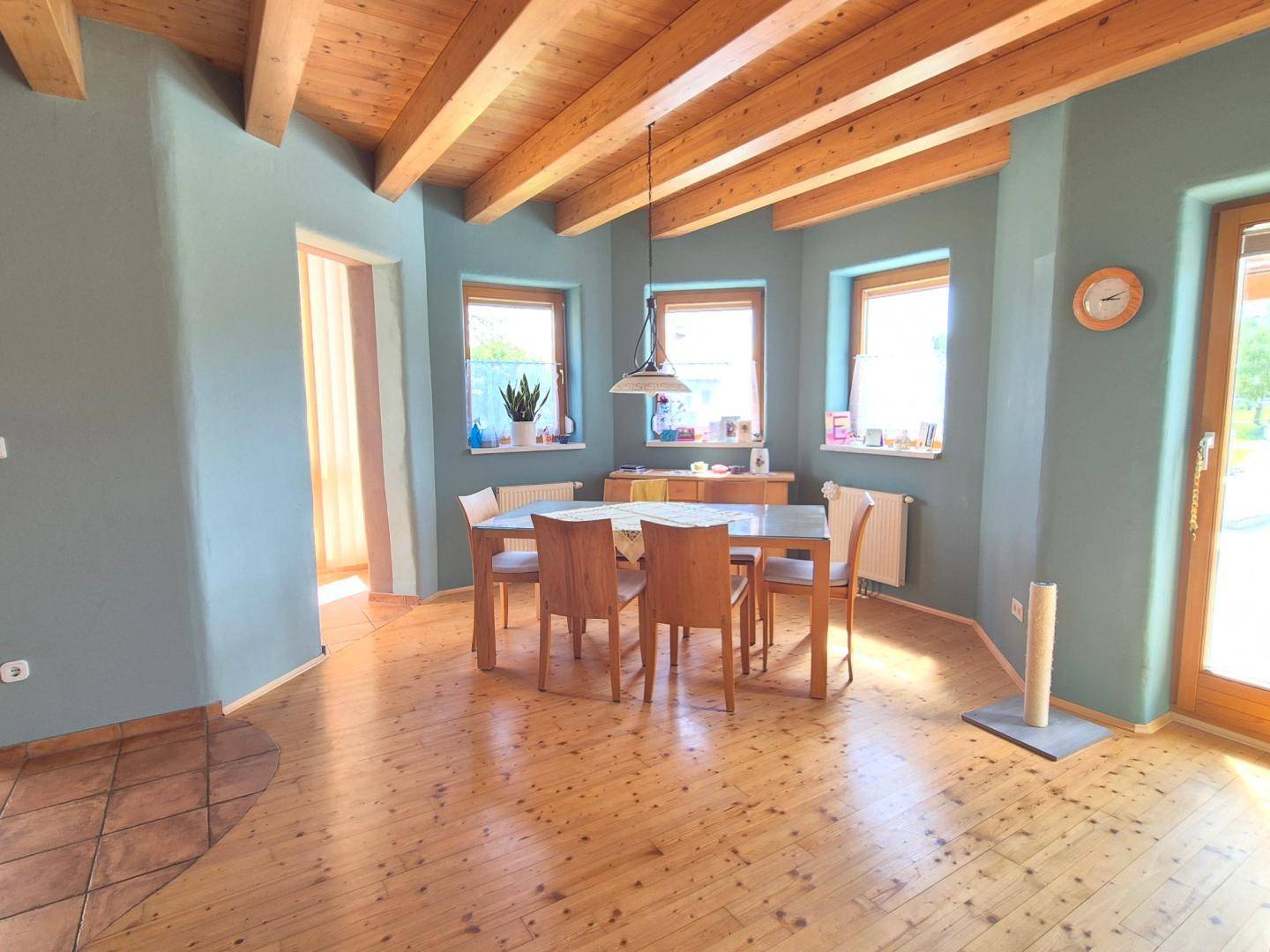 Heller Essbereich mit Holzbalkendecke, Holzboden und hellblauen Wänden.