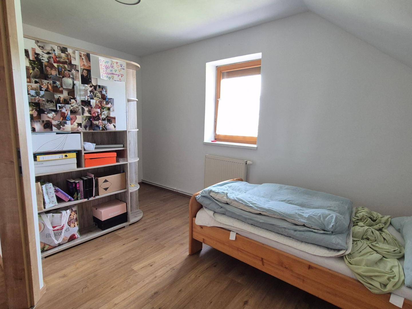 Helles Schlafzimmer im Dachgeschoss mit Schrägen, Laminatboden und einem Fenster.