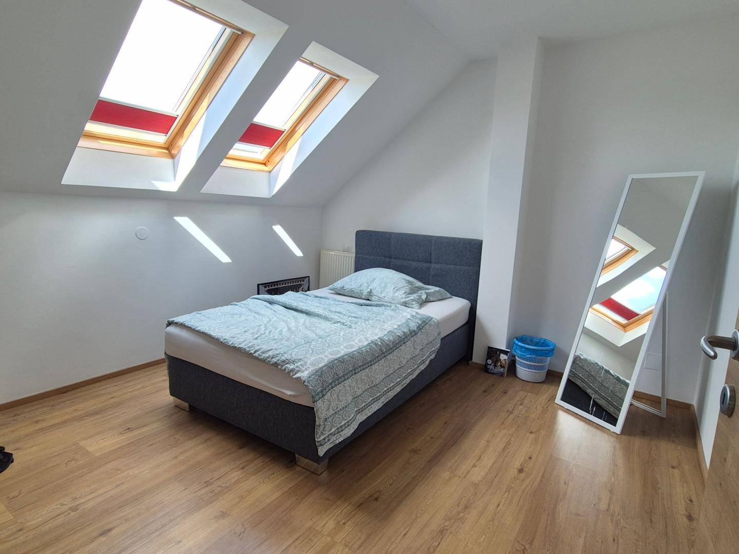 Helles Schlafzimmer im Dachgeschoss mit zwei Dachfenstern und Laminatboden.