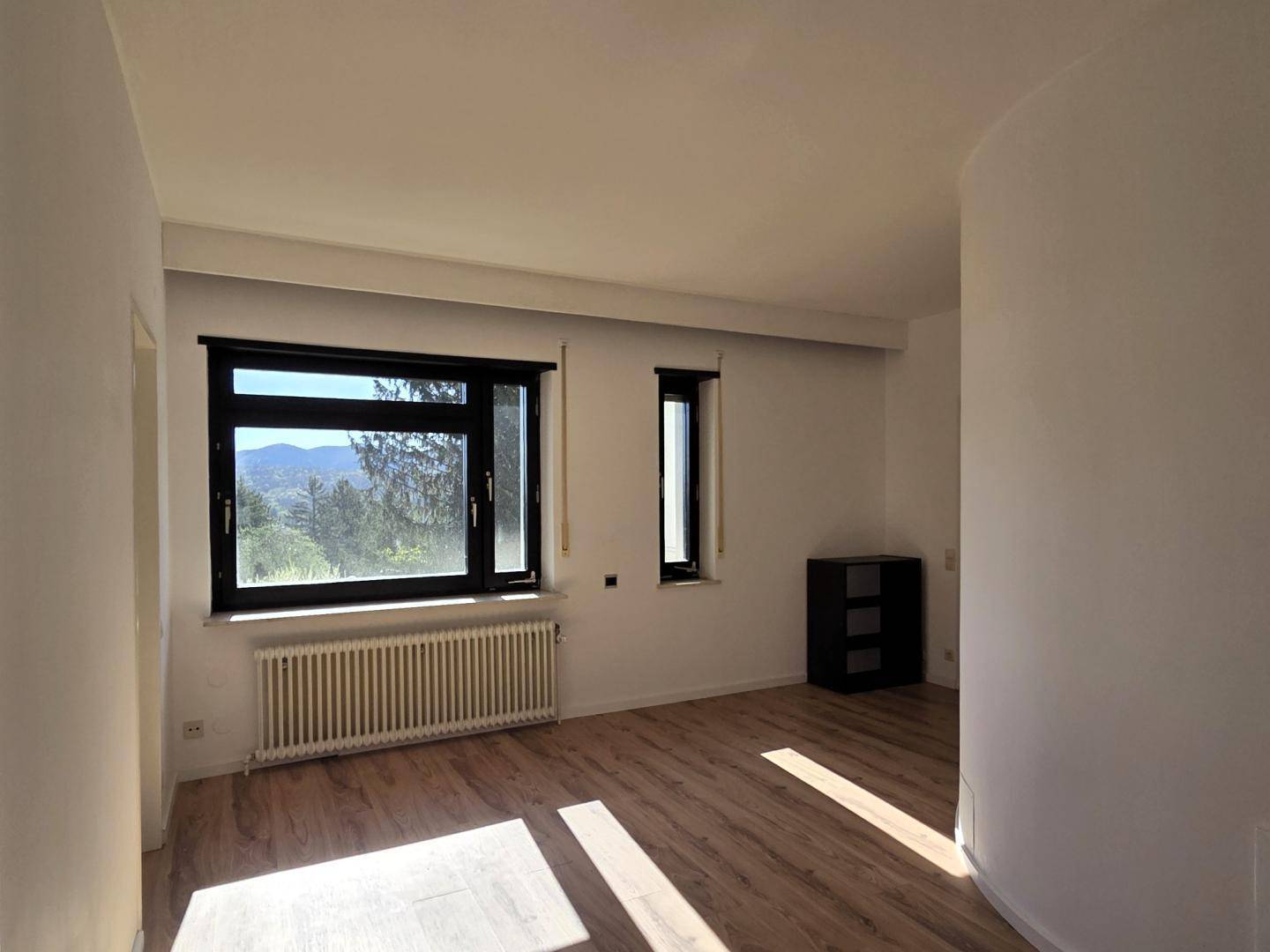 Helles Schlafzimmer mit Laminatboden und zwei Fenstern, bietet viel Tageslicht und Weitblick.