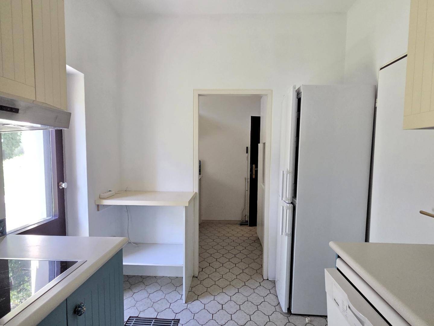 Praktische Küche mit Kühlschrank und Arbeitsfläche, bietet direkten Zugang zu weiteren Räumen.