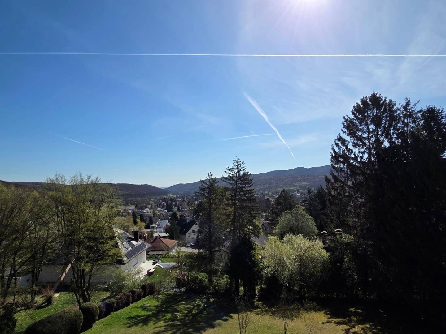 Panoramablick über die grüne Landschaft und die umliegenden Häuser unter blauem Himmel.