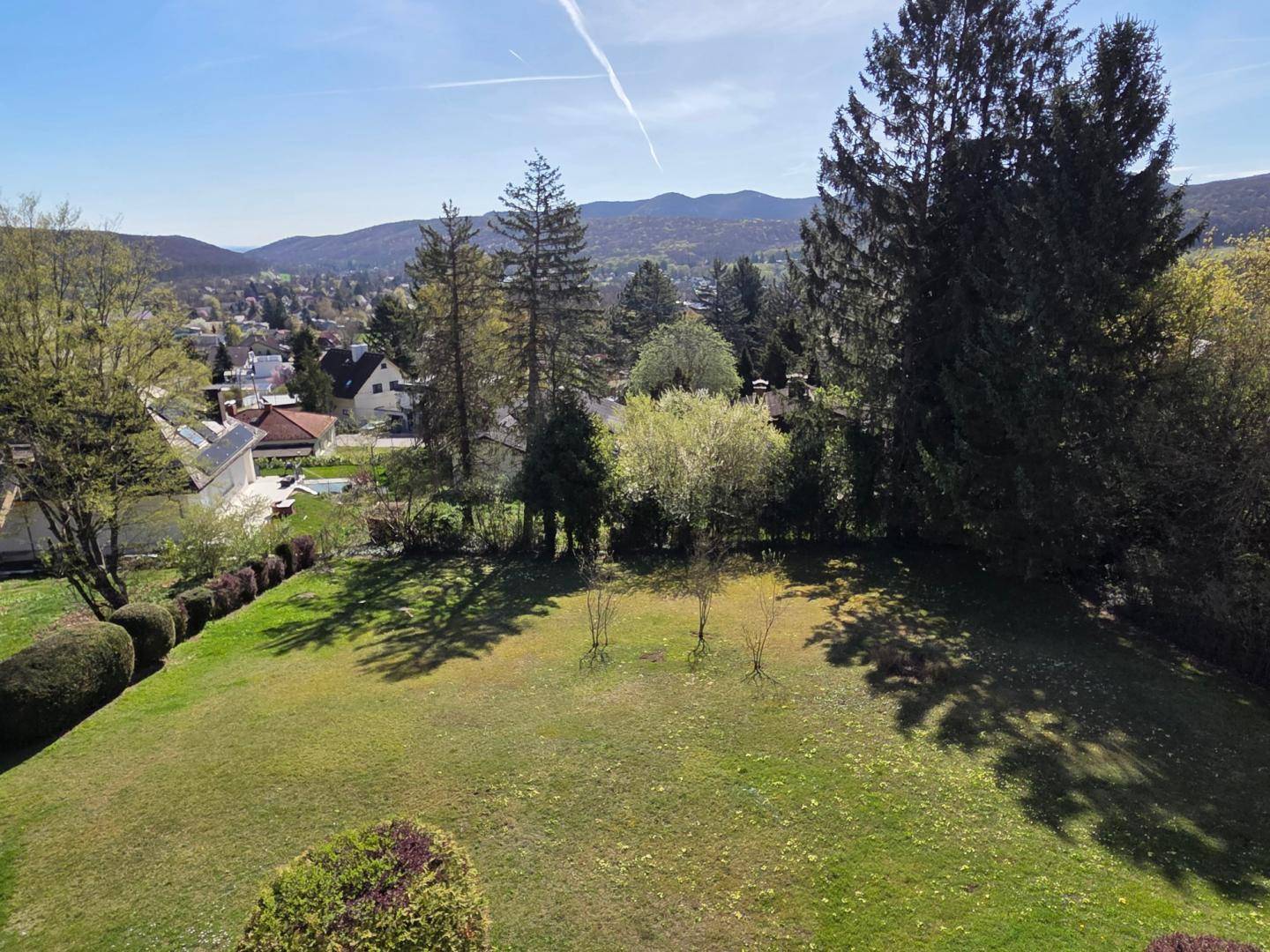 Weitläufiger Blick auf die hügelige Landschaft und die Dächer der Nachbarhäuser an einem sonnigen Tag.