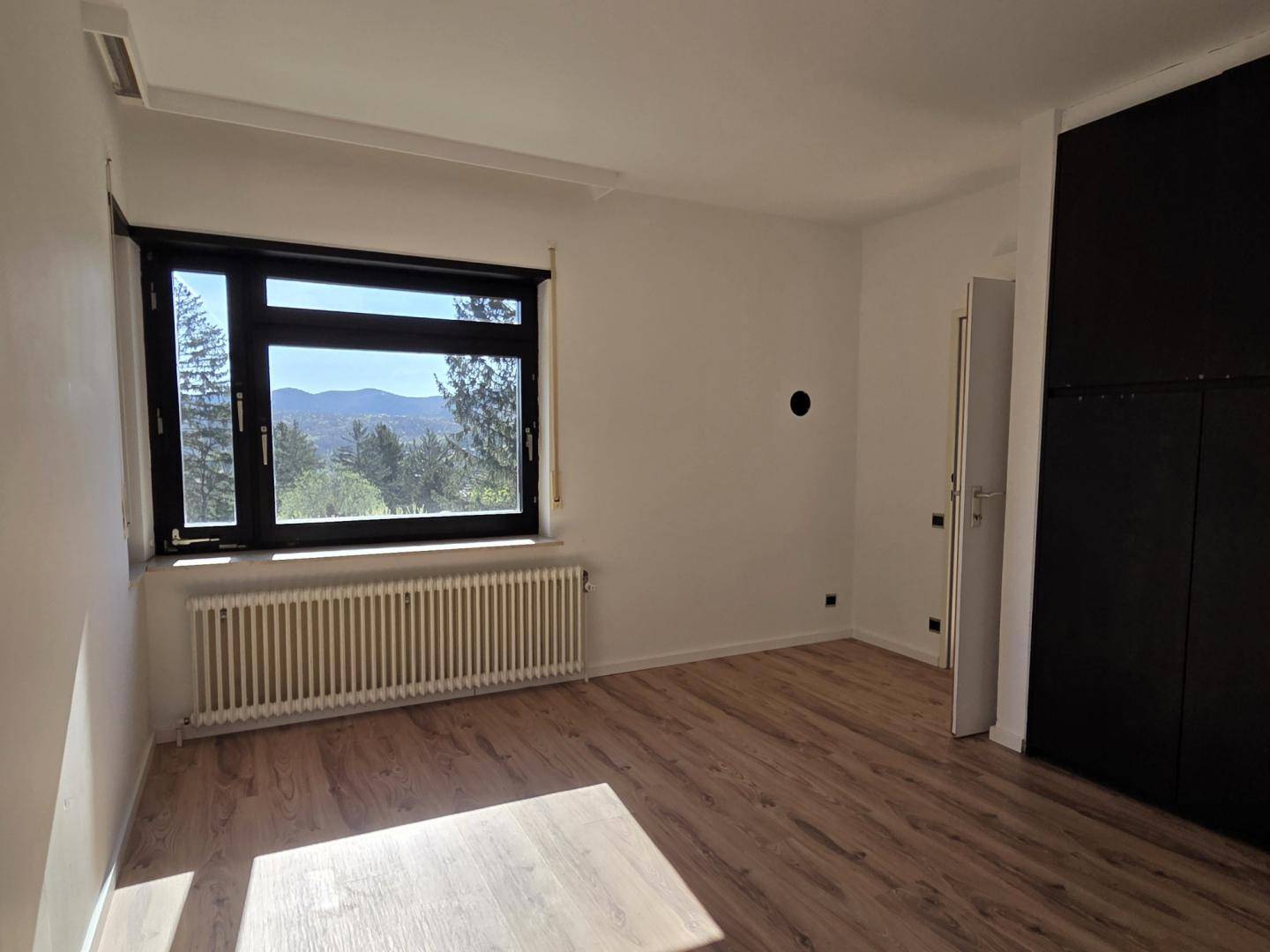 Geräumiges Schlafzimmer mit Laminatboden und großem Fenster, bietet einen schönen Ausblick.