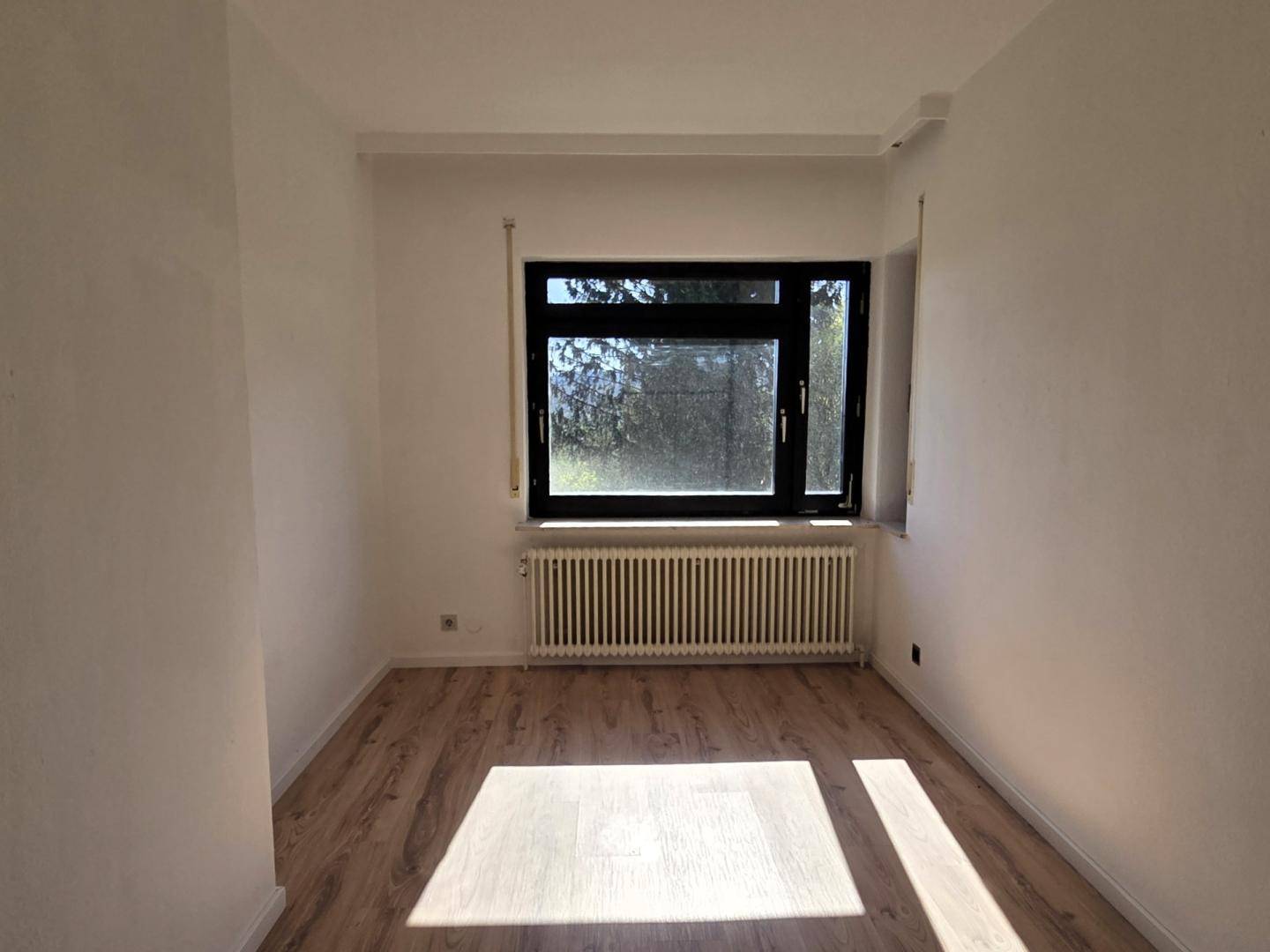 Gemütliches Schlafzimmer mit Laminatboden und Fenster, ideal für Ruhe und Entspannung.