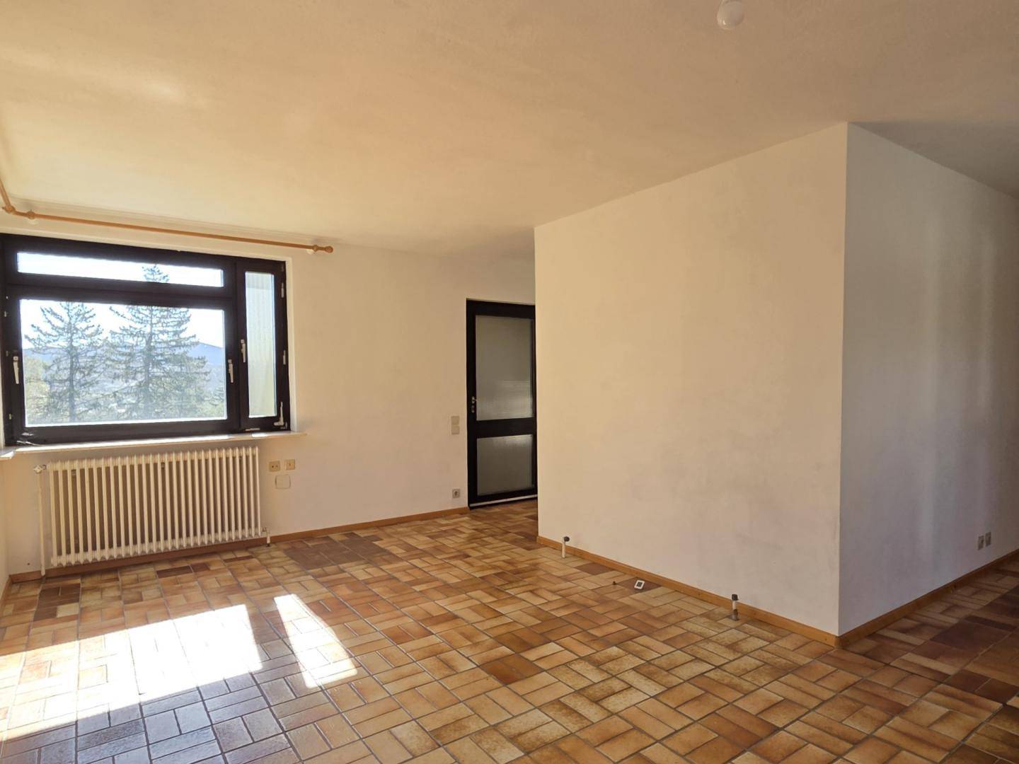 Geräumiges Zimmer mit Terrakotta-Fliesenboden und großem Fenster, bietet viel Tageslicht.