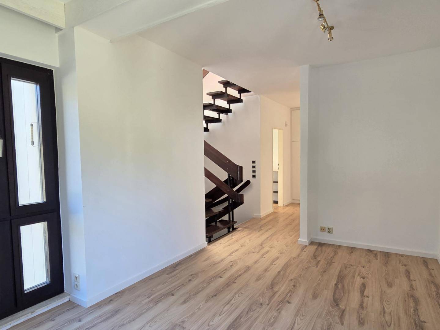 Heller Flur mit Holztreppe und Laminatboden, verbindet die verschiedenen Ebenen des Hauses.