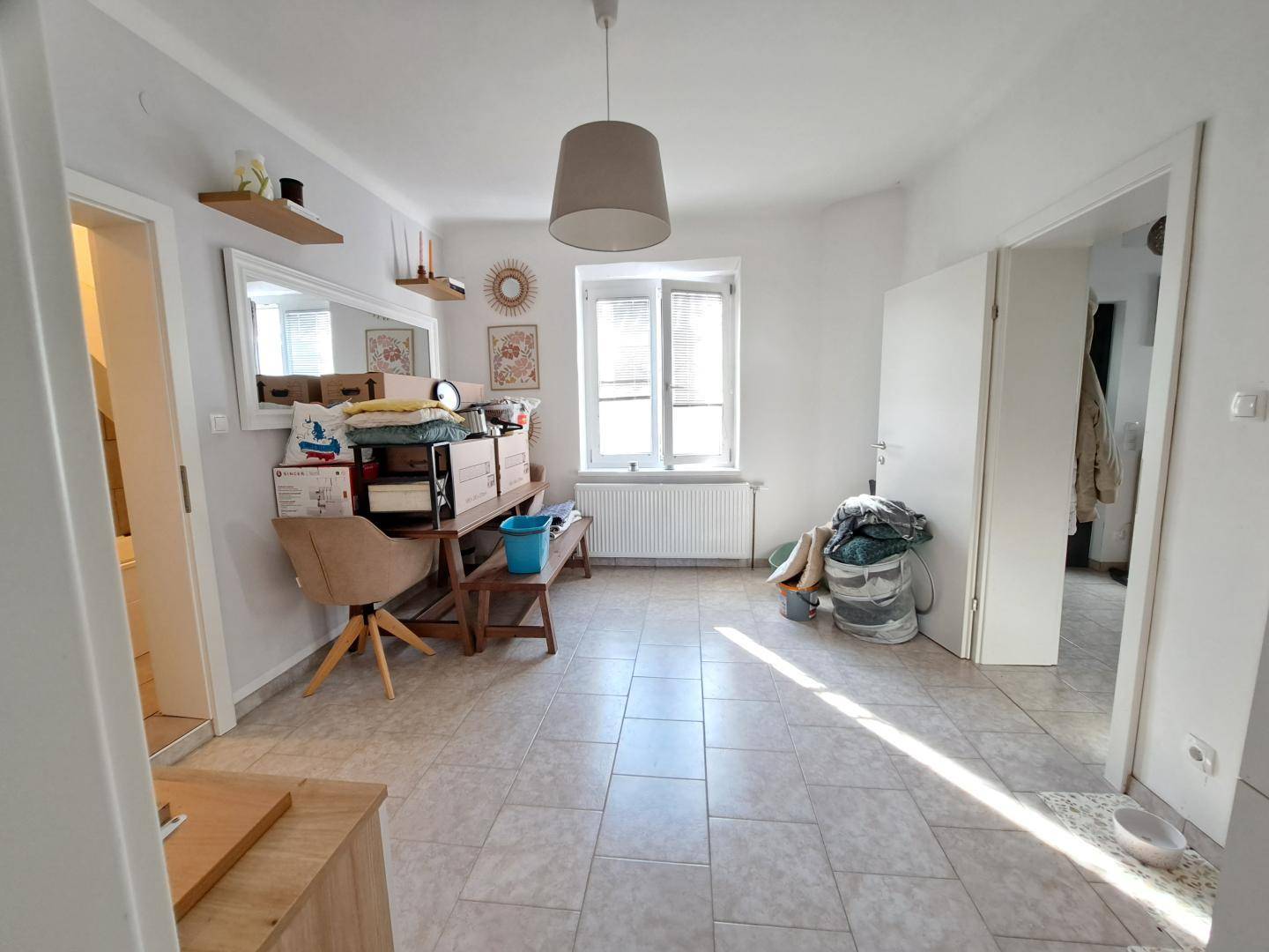 Heller Flur mit Fliesenboden und Fenster, bietet Zugang zu weiteren Räumen.