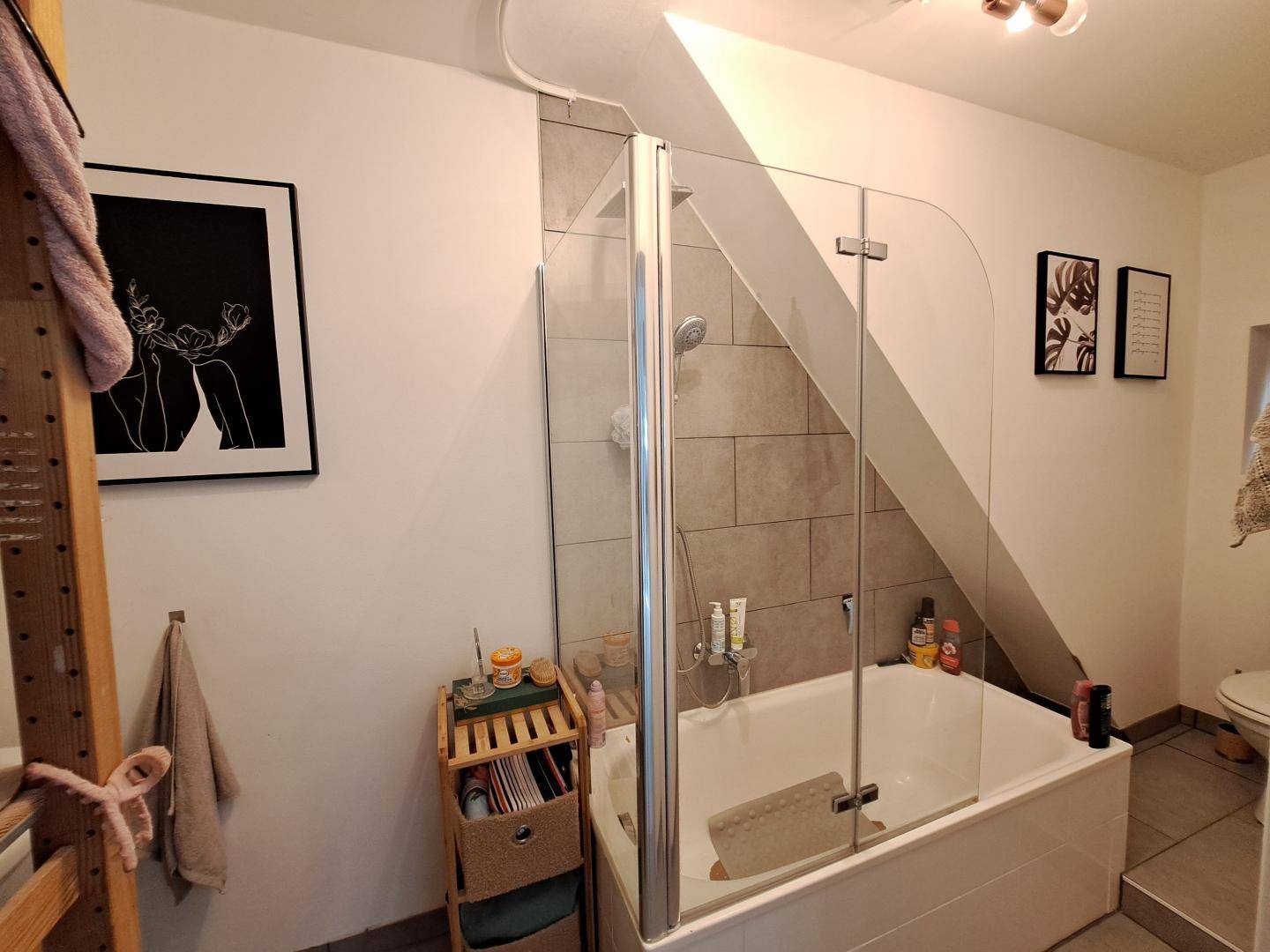 Badezimmer mit Badewanne, Duschabtrennung und Dachschräge, modern gestaltet.