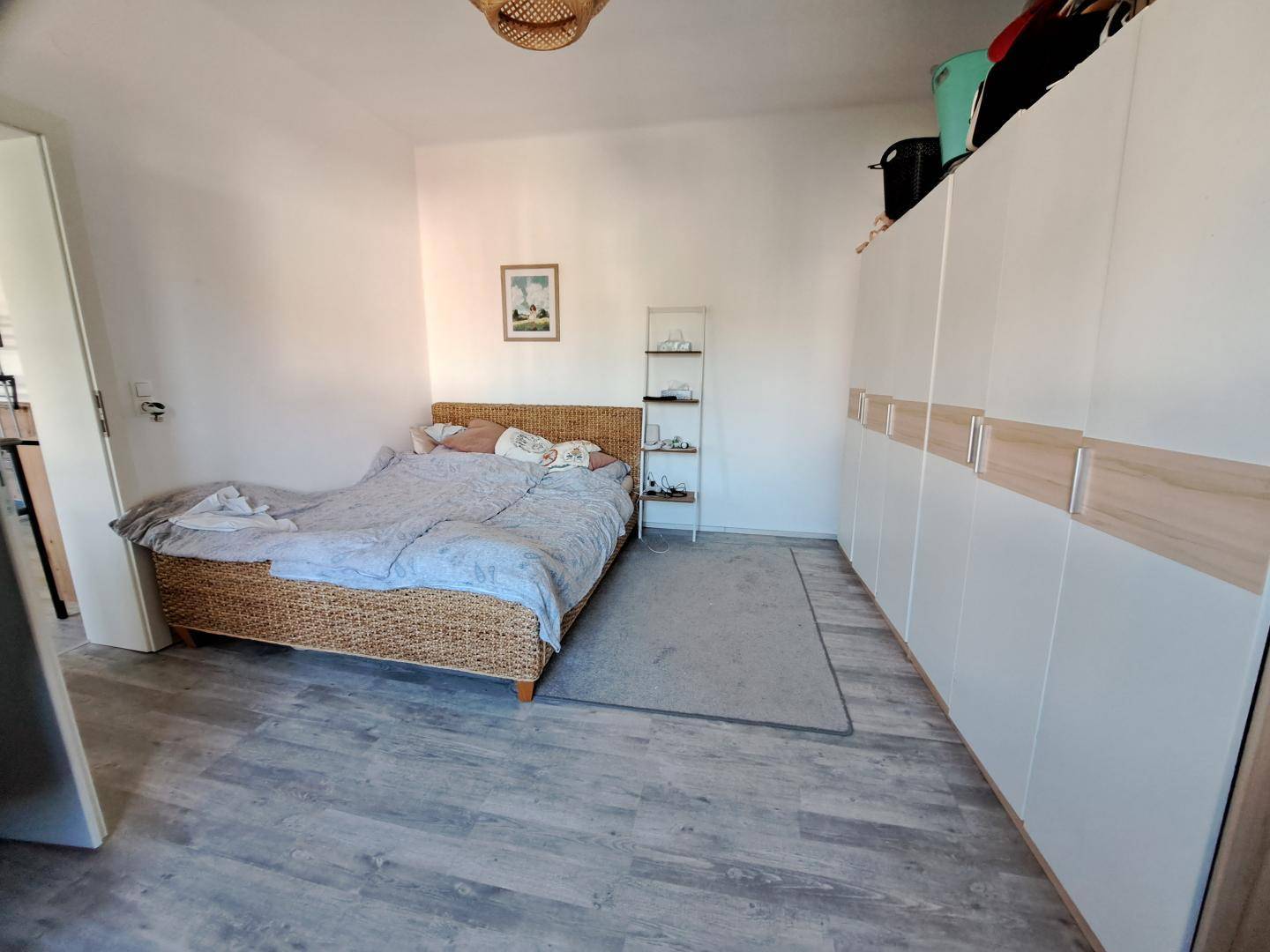 Schlafzimmer mit Doppelbett, großem Kleiderschrank und hellem Vinylboden.