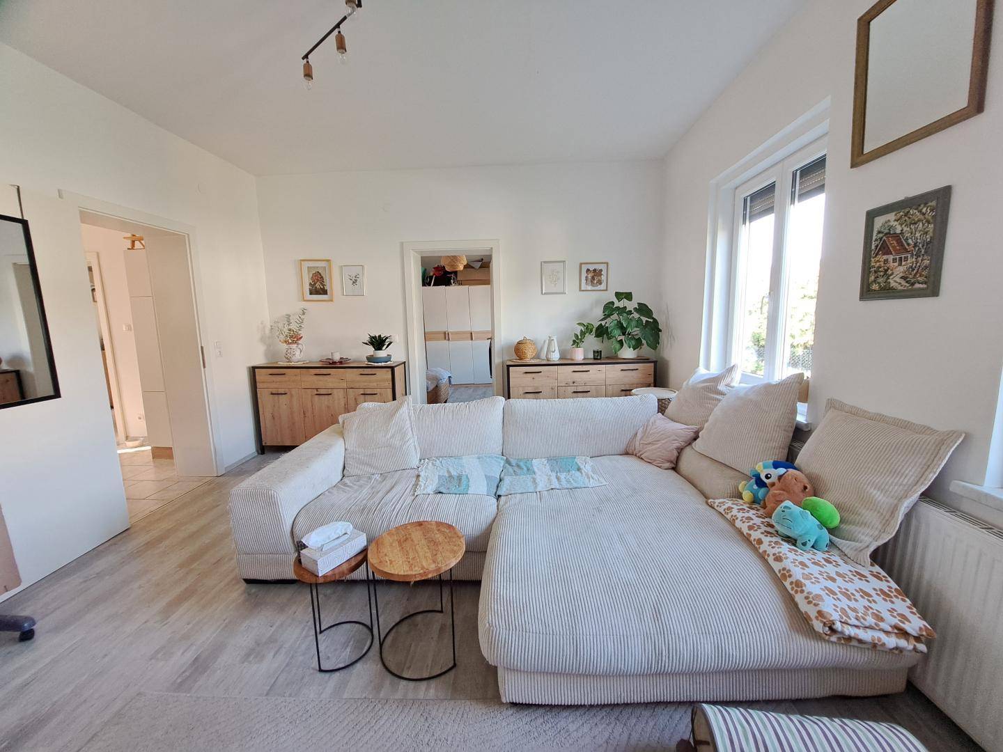 Gemütliches Wohnzimmer mit großem Ecksofa, hellem Boden und moderner Dekoration.