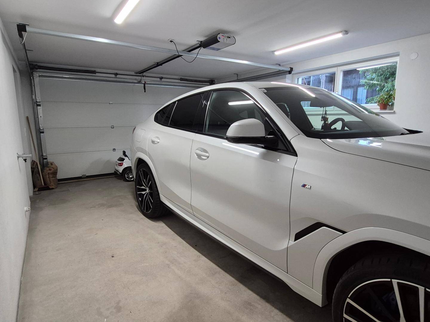 Geräumige Garage mit automatischem Tor, Fenster und ausreichend Platz für ein Fahrzeug.