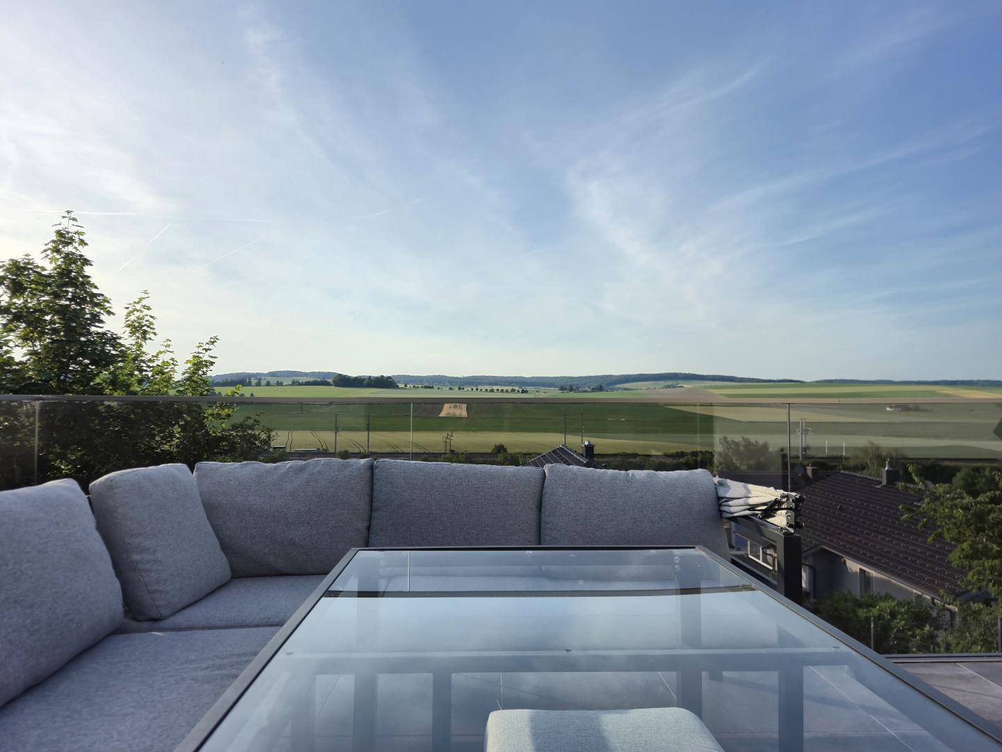 Große Dachterrasse mit bequemen Loungemöbeln und weitem Blick über die grüne Landschaft.