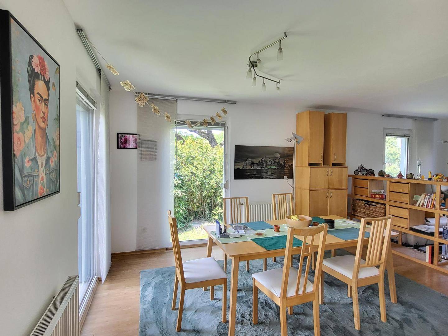Heller Essbereich mit Holztisch, Stühlen und großen Fenstern zum Garten.